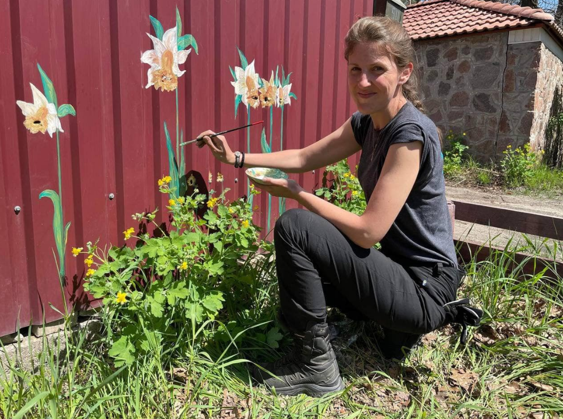 Художниця з Канади малює квіти на дірках від куль у Бучі